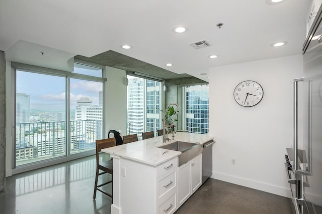 kitchen featuring stainless steel dishwasher, a sink, baseboards, a kitchen bar, and light stone countertops