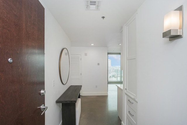 corridor with finished concrete floors, baseboards, and recessed lighting