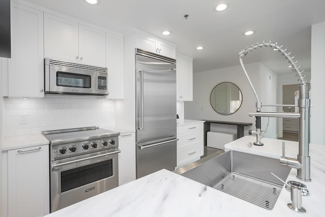 kitchen with premium appliances, white cabinets, light countertops, and recessed lighting