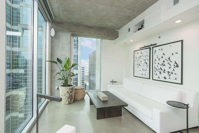 living area with finished concrete flooring, a city view, and floor to ceiling windows
