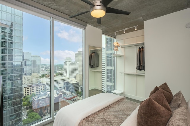 bedroom with a view of city, rail lighting, a closet, and ceiling fan