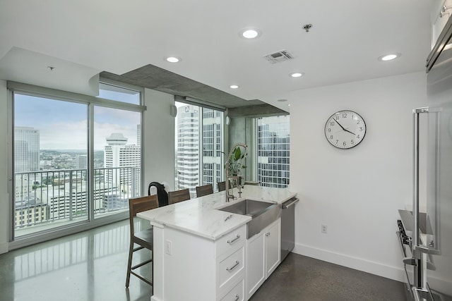 kitchen with baseboards, a breakfast bar area, a sink, stainless steel dishwasher, and white cabinetry