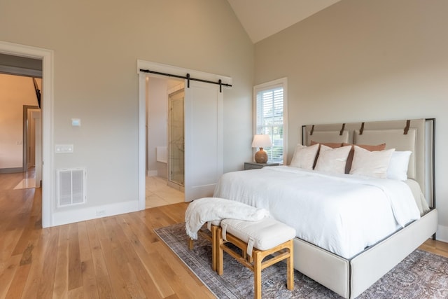 504 Doubleday Ln, Brentwood, TN 37027 - bedroom with a barn door, light wood-style flooring, high vaulted ceiling, baseboards, and ensuite bath