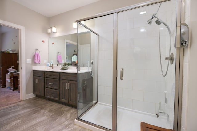 bathroom featuring a stall shower, double vanity, and wood finished floors