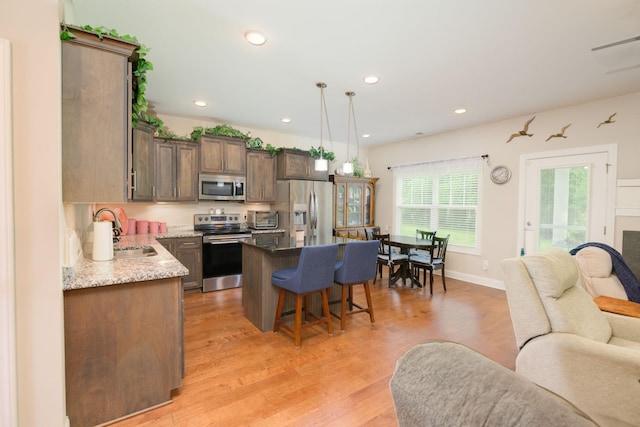 kitchen featuring stainless steel appliances, a sink, open floor plan, a kitchen breakfast bar, and a center island