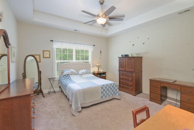 bedroom featuring light carpet, a raised ceiling, a desk, a ceiling fan, and baseboards