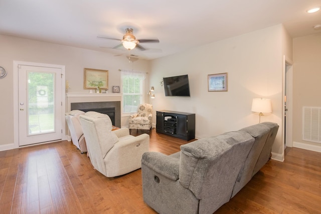 living area featuring a ceiling fan, wood finished floors, a fireplace, and baseboards