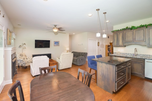 dining area with a ceiling fan, dark wood finished floors, a fireplace, and recessed lighting