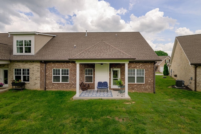 rear view of property with a patio area, brick siding, roof with shingles, a yard, and a ceiling fan