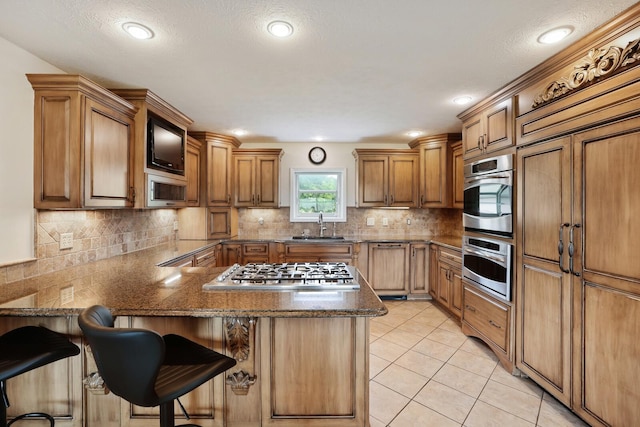 1361 Madison Creek Rd, Goodlettsville, TN 37072 - kitchen with stainless steel appliances, a kitchen bar, brown cabinetry, light tile patterned flooring, and recessed lighting