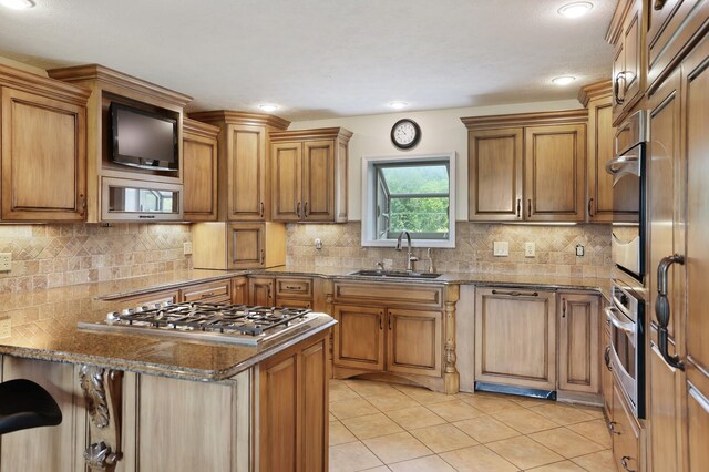 1361 Madison Creek Rd, Goodlettsville, TN 37072 - kitchen featuring appliances with stainless steel finishes, light tile patterned floors, dark stone counters, brown cabinets, and tasteful backsplash
