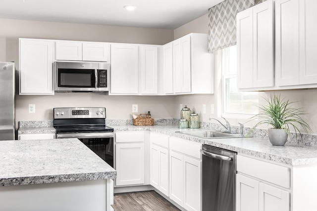 kitchen featuring stainless steel appliances, a sink, light countertops, and white cabinetry