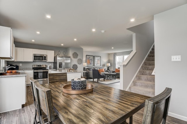 dining room with stairs, recessed lighting, baseboards, and wood finished floors