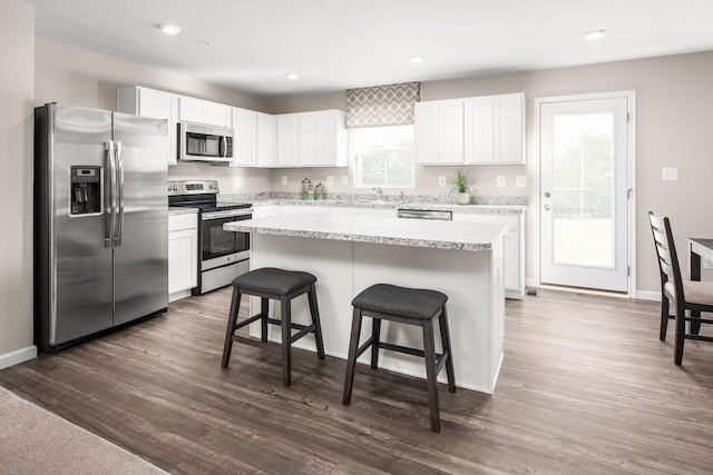 kitchen featuring stainless steel appliances, a kitchen island, a breakfast bar area, white cabinetry, and recessed lighting