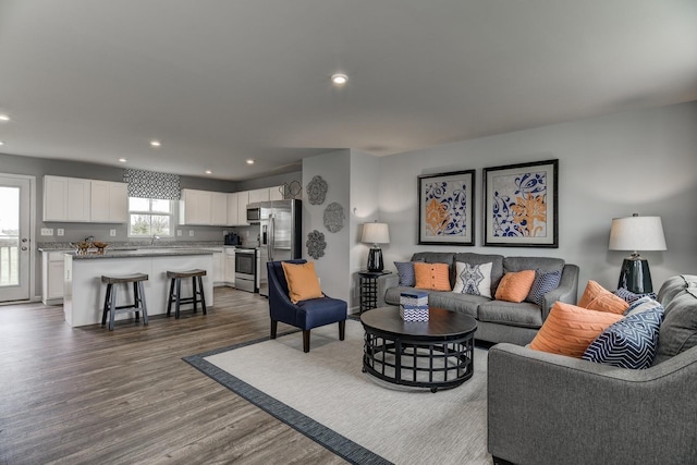 living area with dark wood-style flooring and recessed lighting
