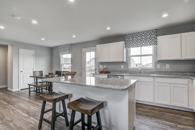kitchen with a sink, a breakfast bar, dark wood-style flooring, white cabinets, and recessed lighting