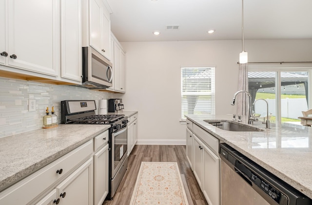 1063 Holland Ridge Way, Lebanon, TN 37090 - kitchen featuring appliances with stainless steel finishes, a sink, wood finished floors, decorative backsplash, and white cabinetry