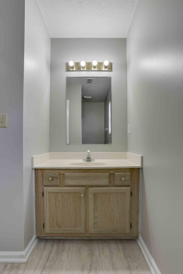 bathroom with baseboards, wood finished floors, and vanity