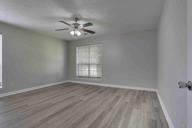 spare room featuring a textured ceiling, wood finished floors, ceiling fan, and baseboards