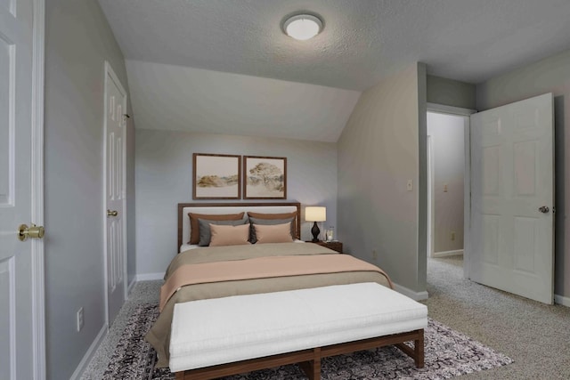 bedroom featuring light colored carpet, lofted ceiling, a textured ceiling, and baseboards