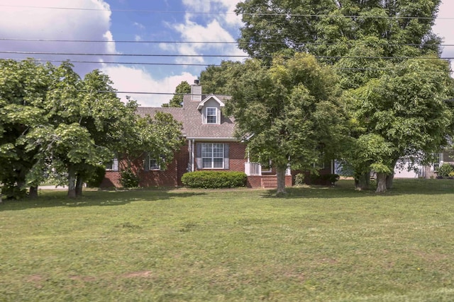 view of front facade featuring brick siding, a front lawn, and a chimney