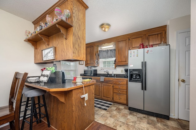 104 Pierce Pl, Unionville, TN 37180 - kitchen featuring stainless steel appliances, a peninsula, a sink, dark countertops, and brown cabinetry