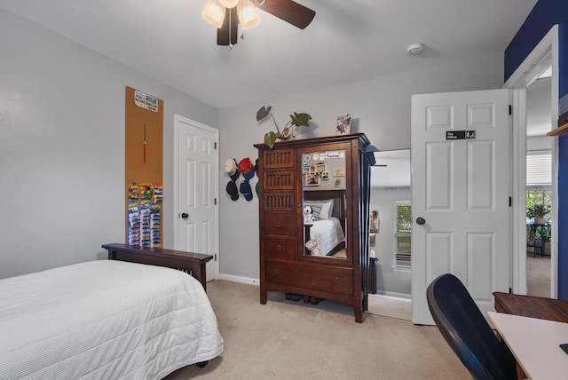 bedroom featuring light carpet, baseboards, and ceiling fan