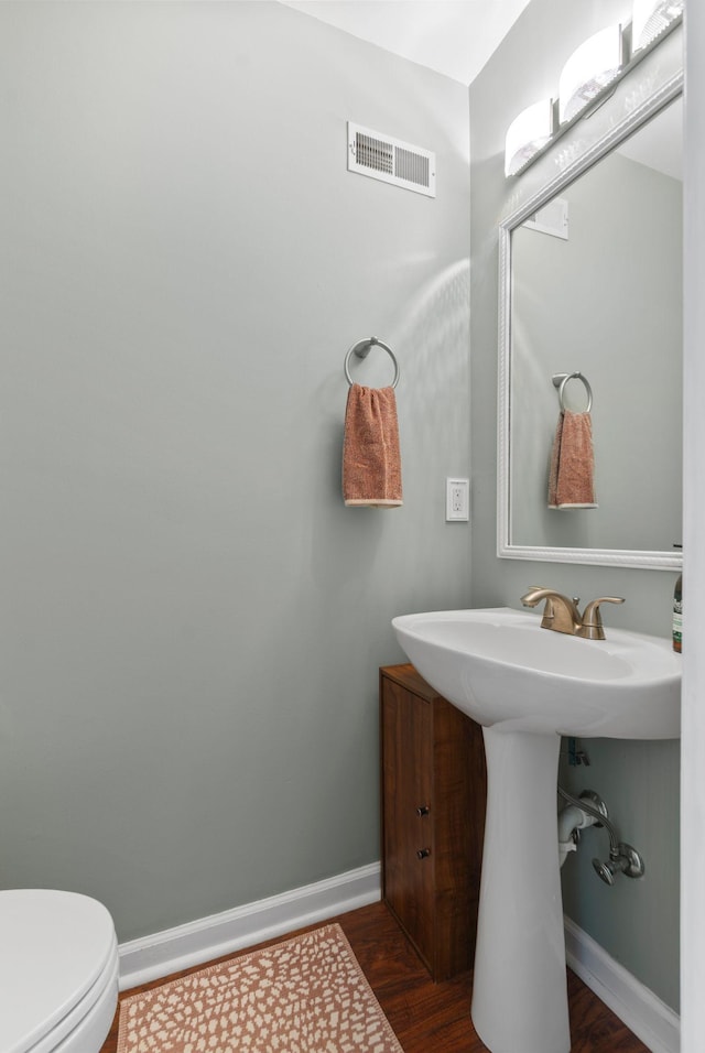 bathroom with wood finished floors, toilet, baseboards, and a sink