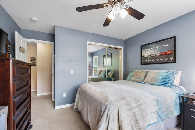 bedroom with a closet, light carpet, baseboards, and ceiling fan