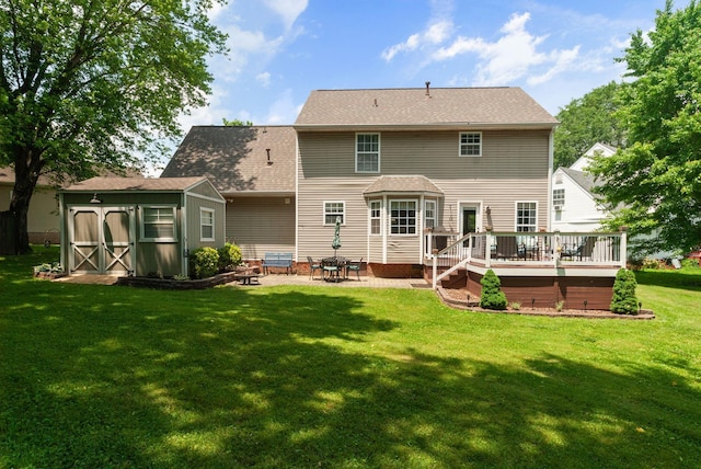 back of house featuring a storage shed, a deck, a lawn, an outbuilding, and a patio area