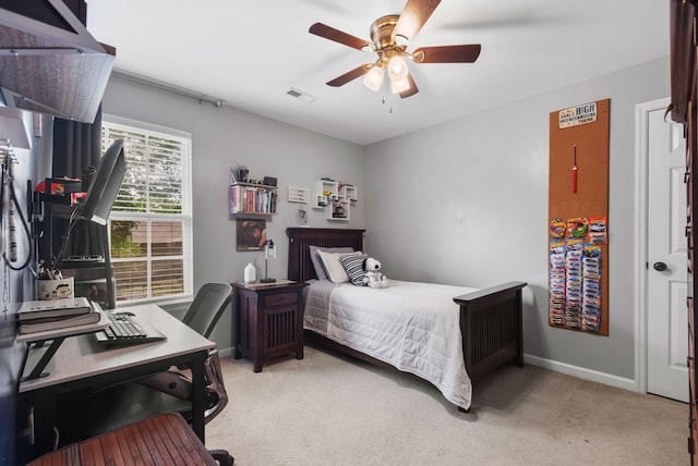bedroom featuring light carpet, baseboards, an office area, and a ceiling fan