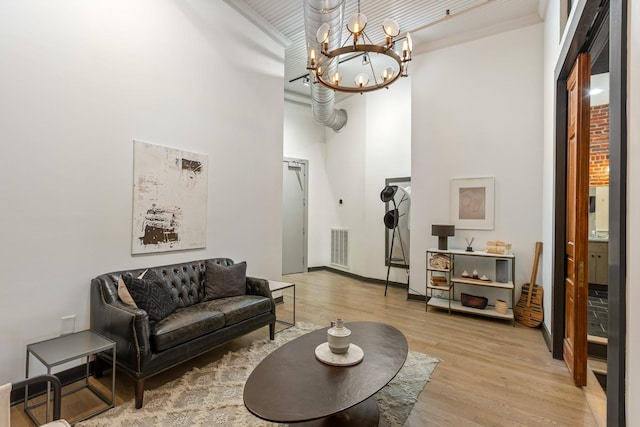 living area featuring wood finished floors, a chandelier, and a high ceiling