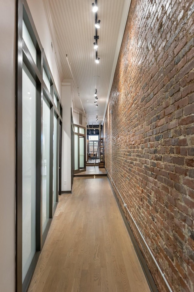 hall featuring ornamental molding, wood finished floors, and brick wall