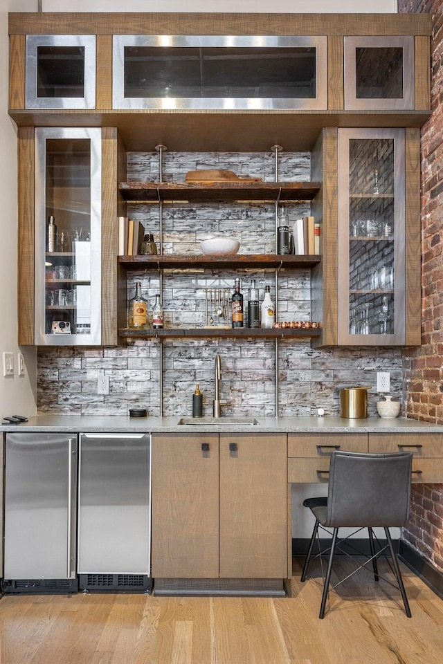 indoor wet bar featuring stainless steel fridge, backsplash, refrigerator, and light wood finished floors