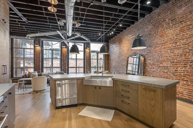 kitchen featuring brick wall, light wood-style floors, a high ceiling, open floor plan, and hanging light fixtures
