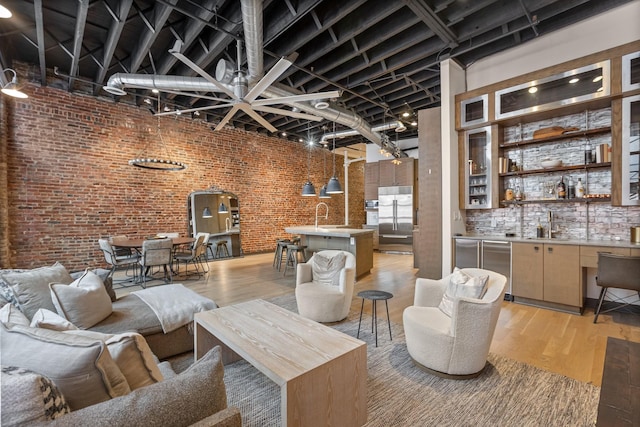 living room featuring brick wall, light wood-type flooring, and a community bar