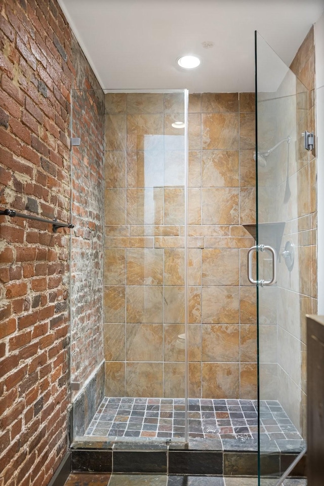 bathroom with a stall shower, brick wall, and recessed lighting