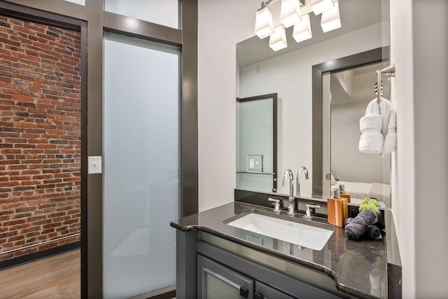 bathroom with brick wall, wood finished floors, and vanity