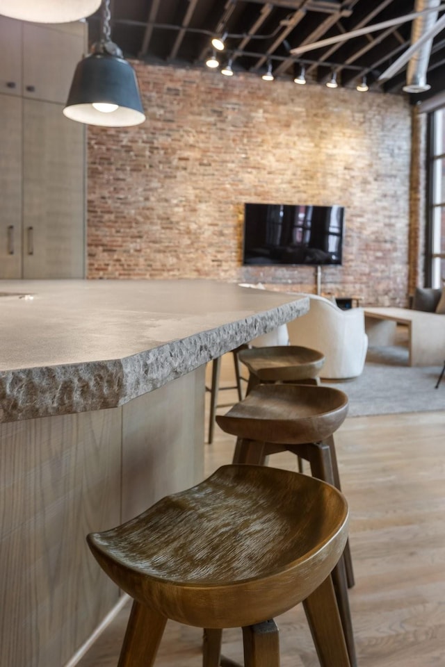bar area with track lighting, wood finished floors, and brick wall