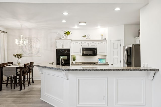 9455 Foothills Ct, Brentwood, TN 37027 - kitchen featuring black appliances, a chandelier, white cabinets, decorative backsplash, and light wood-style floors