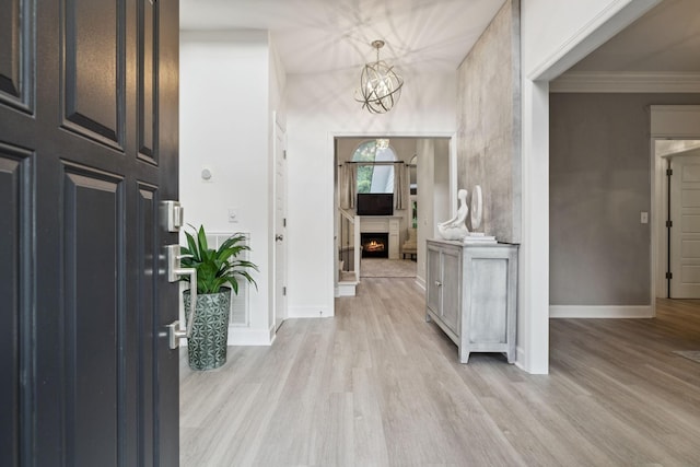 9455 Foothills Ct, Brentwood, TN 37027 - foyer entrance featuring light wood-type flooring, a warm lit fireplace, ornamental molding, and a chandelier