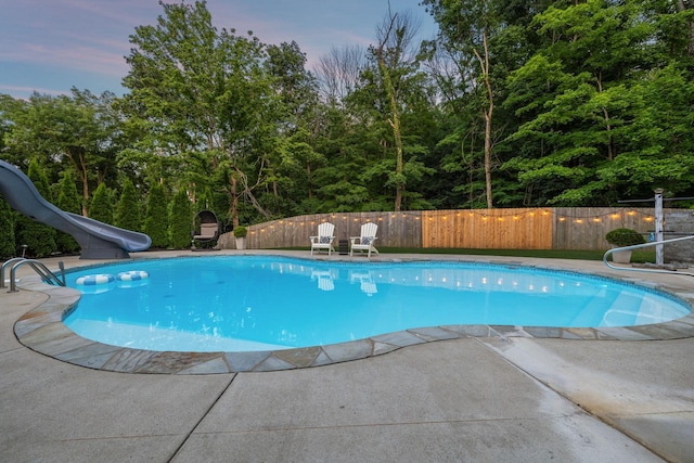9455 Foothills Ct, Brentwood, TN 37027 - pool at dusk featuring a water slide, a fenced backyard, and a patio