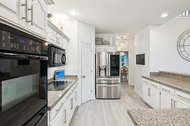 9455 Foothills Ct, Brentwood, TN 37027 - kitchen with black appliances, white cabinets, light wood-type flooring, light stone counters, and decorative backsplash