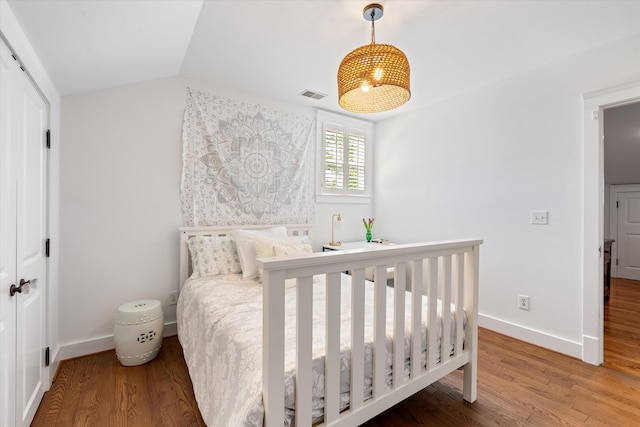 bedroom featuring wood finished floors, baseboards, and lofted ceiling