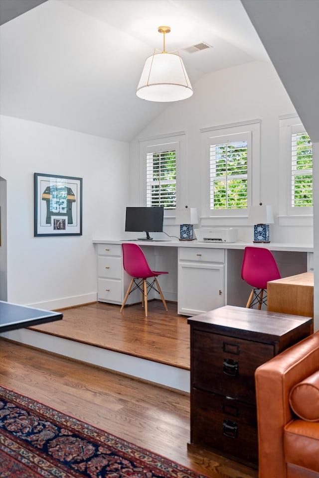 office area with built in desk, wood finished floors, vaulted ceiling, plenty of natural light, and baseboards