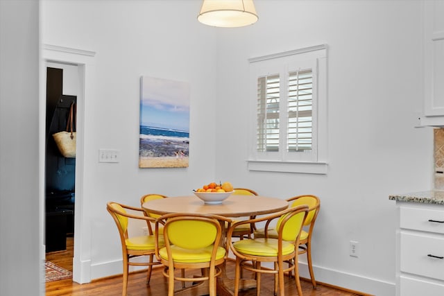 dining area with baseboards and light wood finished floors