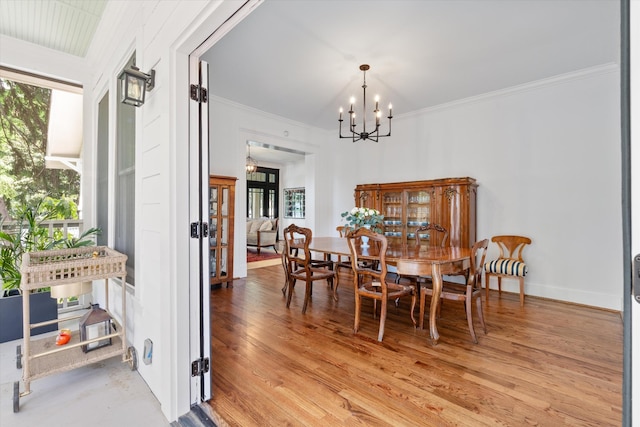 dining room featuring a chandelier, light wood finished floors, crown molding, french doors, and baseboards