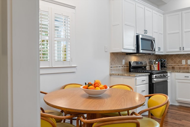 kitchen with appliances with stainless steel finishes, decorative backsplash, healthy amount of natural light, and white cabinets