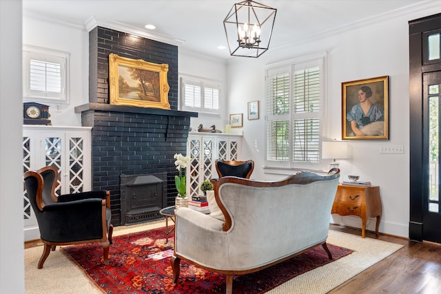 sitting room featuring ornamental molding, wood finished floors, a wood stove, a chandelier, and baseboards