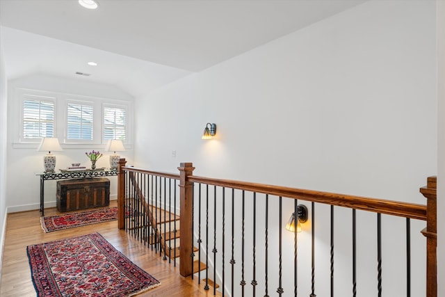 corridor featuring lofted ceiling, wood finished floors, recessed lighting, an upstairs landing, and baseboards